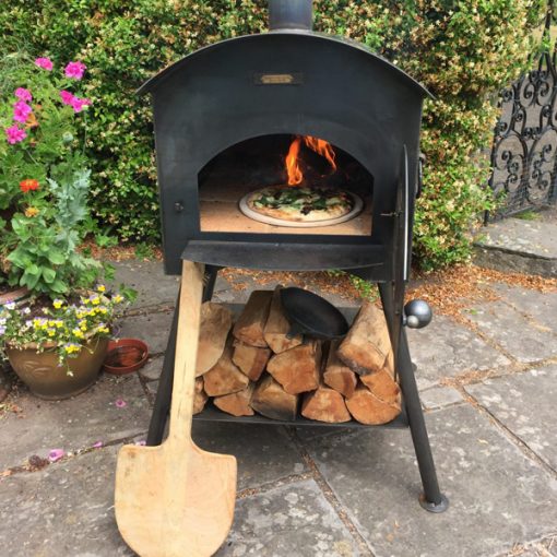 Taditional Pizza Oven Fire Pit Lit with Logs, Paddle and Pizza Lifestyle - Firepits UK - WEB - Lo Res 600x600