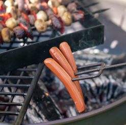 Toasting Fork with sausages on 3 prongs over fire pit