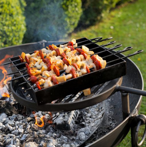 Kebab Rack on Lit Fire Pit with Chorizo and Chicken on Swing Arm BBQ Rack Lifestyle - Firepits UK - WEB - Lo Res