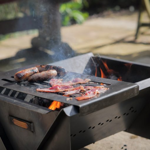 Flat Pack Fire Pit - Lifestyle with sausages and bacon - WEB 600x600 - Lo Res